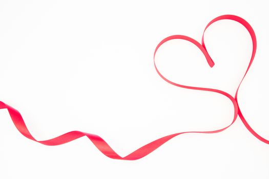 Pink ribbon shaped into heart with copy space on white background