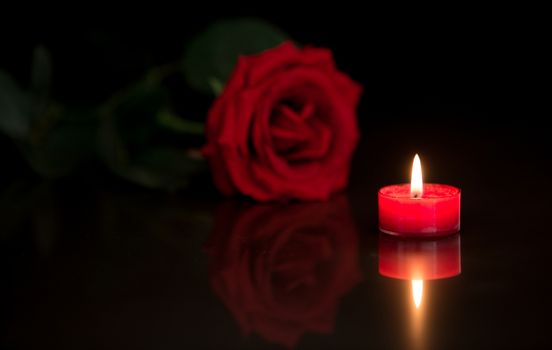 Romantic candle with red rose on black background