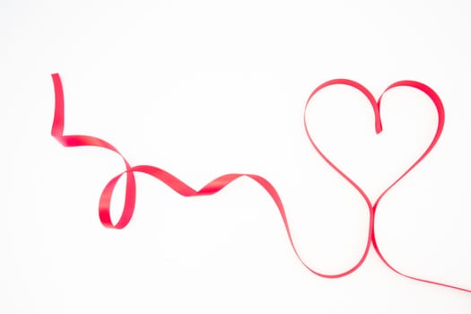 Decorative pink ribbon shaped into heart on white background