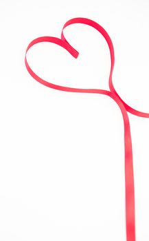 Heart made out of pink ribbon on white background