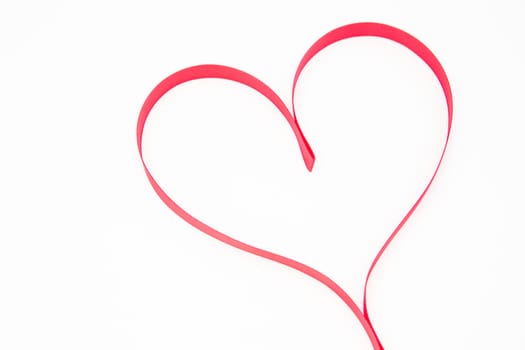 Pink heart shaped ribbon on white background