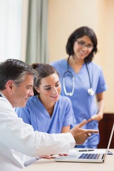 Doctor showing nurses something on laptop in a meeting