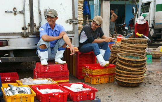 When nothing to do,  two man with smile on their face relax by chat away at fishing market, this make to them funny. July 15, 2013