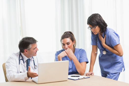 Doctor showing nurses something sad on laptop in a meeting