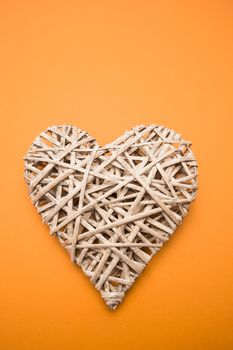 Wicker heart ornament on orange background