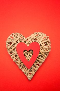 Wicker heart ornament with red cut out on red background
