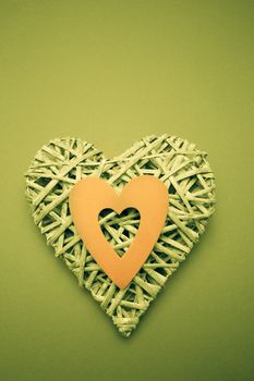 Wicker heart ornament with green paper cut out on green background