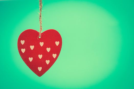 Hanging heart decoration on green background