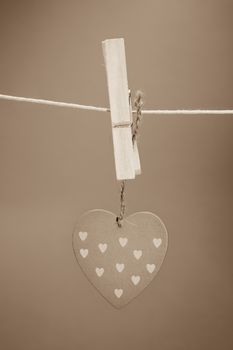 Heart ornament hanging from a peg on a line in grey tint