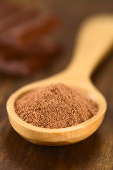 Cocoa powder on wooden spoon with chocolate pieces in the back (Very Shallow Depth of Field, Focus one third into the cocoa)