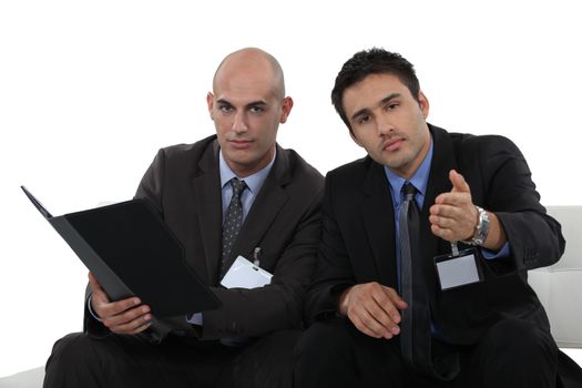 two young businessmen sitting on a couch