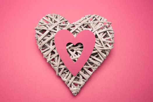 Wicker heart ornament with paper cut out on pink background