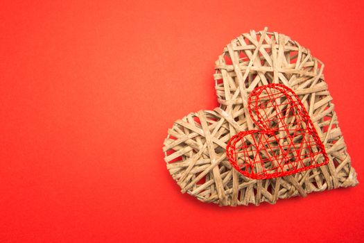 Wicker heart ornament and red heart shaped box on red background