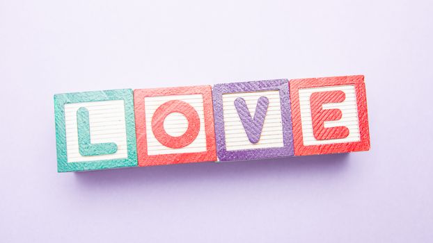 Building blocks spelling out love on purple background