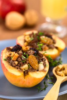 Savory baked apple filled with mincemeat, raisins, sultanas, onion and walnut, sprinkled with fresh thyme leaves on top (Selective Focus, Focus on the sultana in the front)   