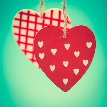 Two hanging heart ornaments on green background