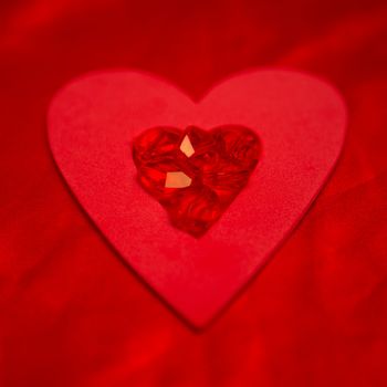 Rubies resting on red heart on red silk