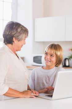 Granny and grandson using laptop in kitchen