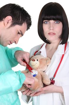 Surgeon with assistant operating teddy bear
