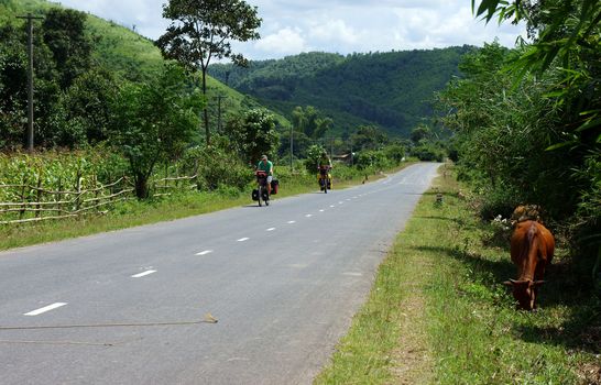 Traveller ride bicycle on the road conect Dalat to Daklak, this is the nice road with fresh air, neglected landcape. Viet Nam- September 3, 2013