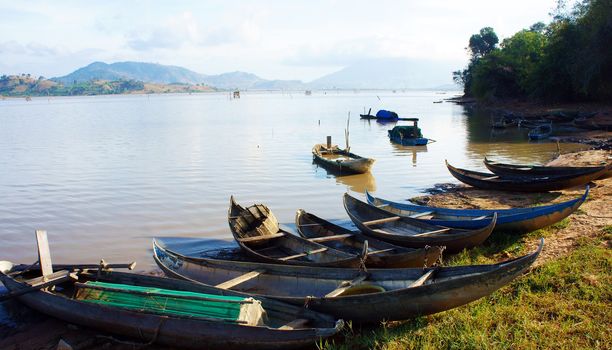 at Lak lake, small bamboo crafts lay on the shore under sunlight. That make beautiful, peaceful landscape. This lake is where many fishing boat rowing everyday, after work they were attached to the border.