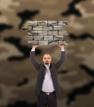 Businessman holding a large piece of a brick wall, camouflage pattern , isolated