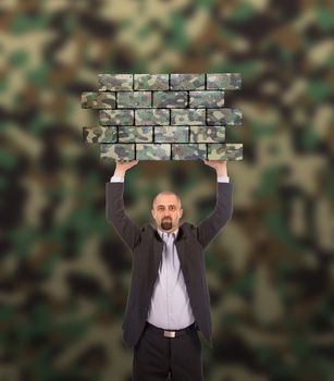 Businessman holding a large piece of a brick wall, camouflage pattern , isolated