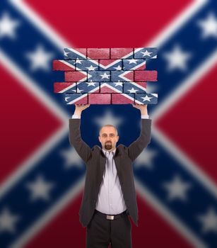 Businessman holding a large piece of a brick wall, Confederate flag, isolated