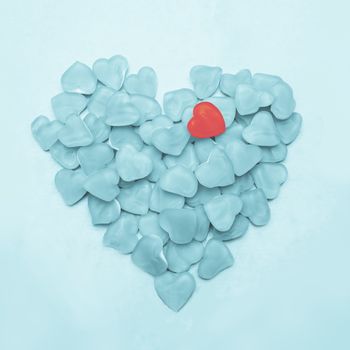 Blue heart made of candy with one pink heart on blue background