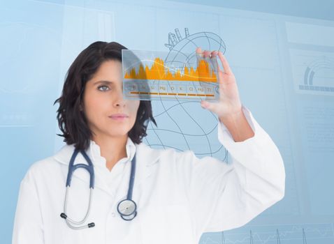 Brunette serious doctor looking at a graph with futuristic technology