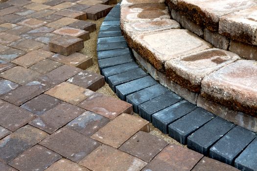 Progress on building brown brick patio steps with contrasting bluish color bricks