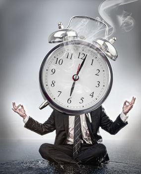 Businessman meditating with face covered by giant smoking alarm clock