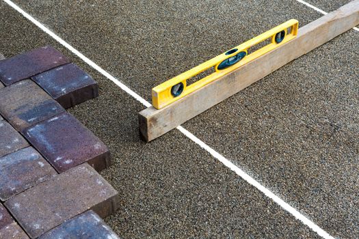 Paving job gets done preciously leveling the sand with yellow level and piece of wood