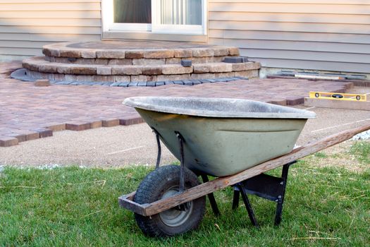 Building Brick Patio with Barrel and level, newly built steps with slopes at background,a clean patio job completion almost done