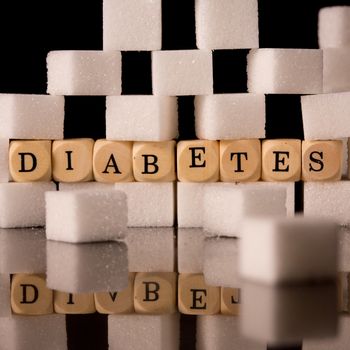 Close up on sugar cubes and dice spelling diabetes on black background