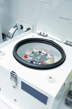 A centrifuge in the laboratory workroom of a pathology medical blood collection clinic.  The cientrifuge is holding various tubes, sst, edta, k2 trace element, glucose, k2 edta for hematology blood banking