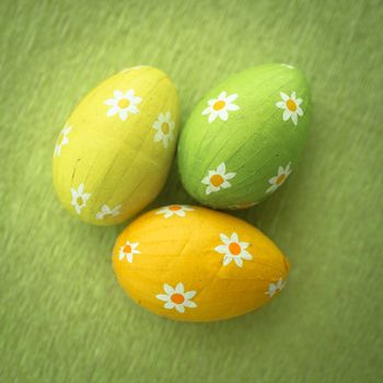 Three floral pattern foil wrapped easter eggs on green surface