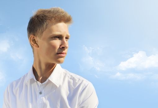 Handsome blond man on blue sky background at sunny day