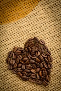 Heart made of roasted coffee beans on burlap sack