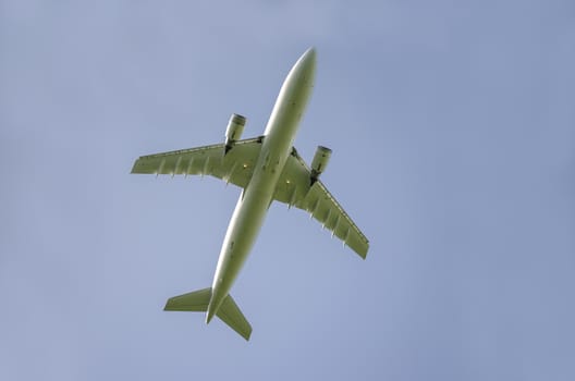 Bottom view of airplane taking off on a clear blue sky.