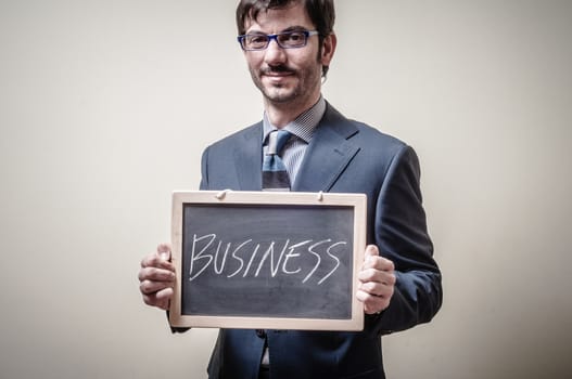businessman holding blackboard written business on gray background