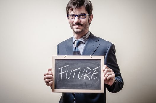 businessman holding blackboard written future on gray background