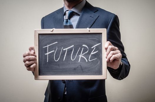 businessman holding blackboard written future on gray background