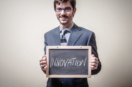 businessman holding blackboard written innovation on gray background