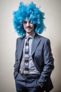 funny businessman with blue wig on  gray background
