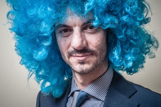 funny businessman with blue wig on  gray background