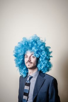 funny businessman with blue wig on  gray background