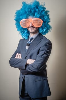 funny businessman with big orange glasses and blue wig on gray background