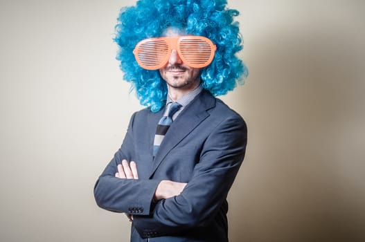funny businessman with big orange glasses and blue wig on gray background