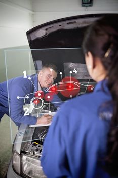 Smiling mechanic looking up at colleague with a futuristic interface with car diagram and statistics